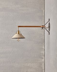 a lamp hanging from the side of a wall next to a light fixture on a concrete wall