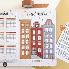 an open planner with buildings on it next to a roll of washi tape and a marker