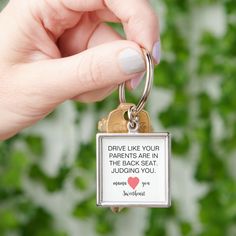 a person holding a keychain with a quote on it that says drive like you parents are in the back seat judging you