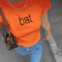 Bat Brat Style Baby Tee 🦇   Get ready for Brat Autumn with our "Bat" brat style shirt! This bright orange tee is the perfect way to show off your brat side with a funny fall twist. Whether you're heading to a fall music festival, a pumpkin patch, or just want to make a statement at a Halloween party, this brat-inspired baby tee is sure to make a statement.  Crafted from 100% cotton, this youth-sized tee is intentionally shrunken to achieve that effortless 90s baby tee look. Please refer to the size chart carefully to ensure the perfect fit. Our models are all wearing an XS and typically wear a size small. For the best fit, we recommend measuring a baby tee you already own to compare sizing. Brat Pumpkin, Halloween Streetwear Tops With Logo Print, Fitted Y2k T-shirt For Halloween, Halloween Logo Print Tops For Streetwear, Y2k Halloween T-shirt For Streetwear, 90s Style Halloween Streetwear Top, Fitted Casual Halloween Tops, Fitted Casual Tops For Halloween, Orange Letter Print Tops For Streetwear