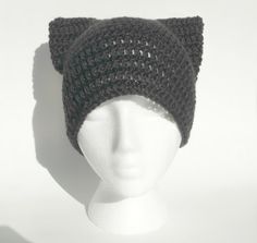 a white mannequin head wearing a black knitted cat ear hat with ears