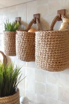 three baskets hanging on the wall with plants in them