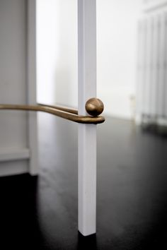 a close up of a door handle on a wooden floor with white walls and black floors