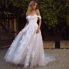 a woman in a white wedding dress standing on the ground with her hand on her hip