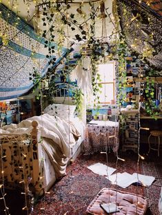 a bedroom with lots of hanging plants and decorations on the ceiling, along with an unmade bed