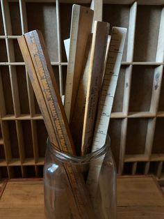 a glass jar filled with wooden rulers on top of a table