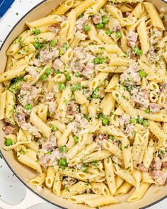 a skillet filled with pasta, peas and meat in sauce on top of a white table