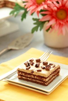 a piece of cake sitting on top of a white plate next to a pink flower