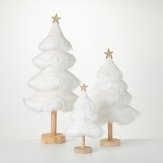 three white christmas trees with gold stars on them