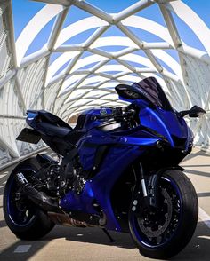 a blue motorcycle parked in front of a white bridge