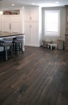 a large kitchen with wooden floors and white cabinets