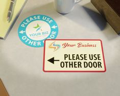 a close up of a sign on a table with a cup and pen in the background