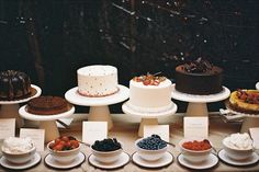 a table topped with lots of cakes and desserts on top of white plates next to each other