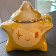 a yellow ceramic teapot with a smiley face on it