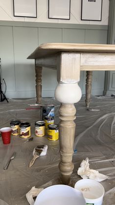 the table is being painted with white paint and some buckets on the ground next to it