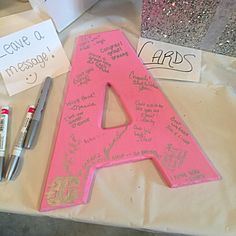 a pink letter sitting on top of a table next to some markers and paper notes