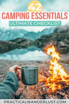 a person holding a cup over a campfire with the words camping essentials ultimate checklist