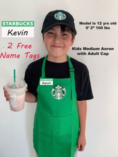 a young boy wearing an apron and holding a starbucks drink