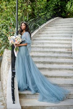 a woman in a blue dress standing on some steps