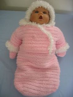 a baby doll that is wearing a pink knitted outfit and white trimmings