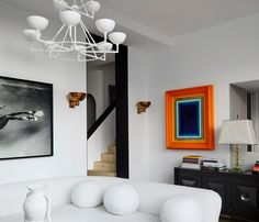 a living room filled with white furniture and art