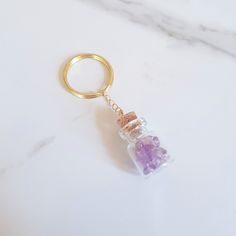 a gold keychain with a purple stone in it on a marble countertop