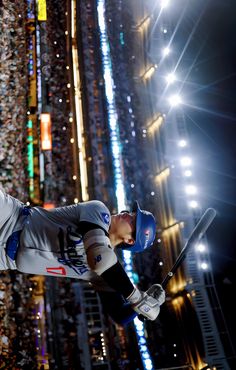 a baseball player is in mid air after hitting the ball with his bat at night