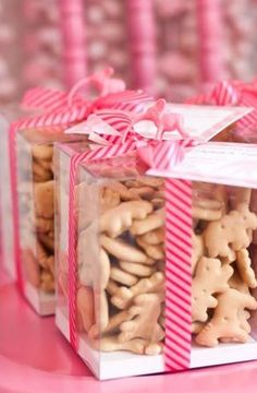 two boxes filled with cookies sitting on top of a pink table covered in candy canes