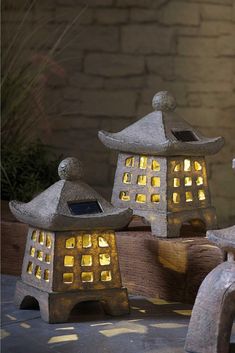 three stone lanterns lit up in front of a brick wall