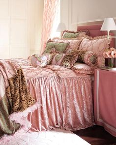 a bedroom with pink bedding and leopard print on the comforter, pillows and lamps