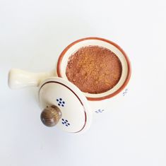 a white cup filled with brown powder next to a snail