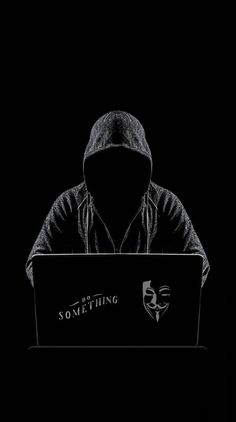 a man in a hoodie is using a laptop on the dark background, while wearing a mask