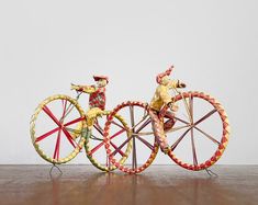 two toy figurines on top of each other near a bicycle wheel and spokes