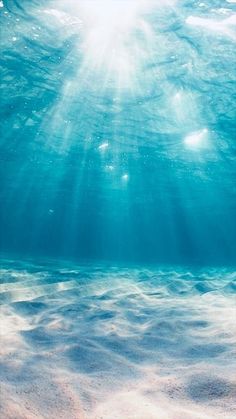 the sun shines brightly through the water's surface as it floats over sand