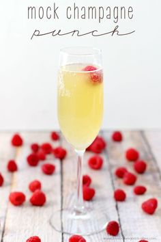 a glass filled with champagne and raspberries on top of a wooden table next to the