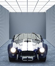 a blue and white sports car parked in front of a wall