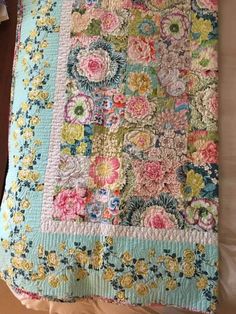 a quilt is laying on top of a bed and it's cover has flowers all over it