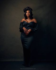 a woman in a black dress posing for the camera with her hands on her hips