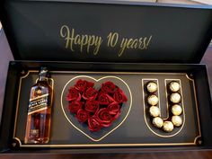 a bottle of booze and two roses in a gift box with the letter u