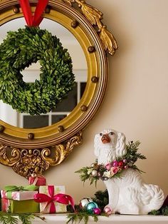 a dog figurine sitting on top of a mantle next to a christmas wreath