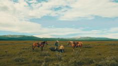 three people are standing in the grass with horses