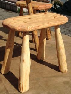 a wooden bench made out of logs sitting on the ground in front of a building