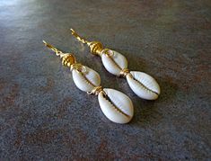 "Sea Shell Earrings, Beach Jewelry, Triple Cowrie Shell Earrings, Cowry Shells, Ethnic Dangle Earrings, African Earrings Double Cowrie Shell Dangle Earrings should definitely be in your jewelry wardrobe. This three row tier aligns perfectly well with the boldness of of gold to compliment, Approx 3.5\" length, copper ear wires. Cowrie shells were the most popular currency within Africa. Pictures of cowrie shells adorned cave walls. The Egyptians considered them to be magical agents and also used Traditional Nickel-free Earrings For Beach, White Bohemian Pierced Earrings, Bohemian White Wire Wrapped Earrings, White Wire Wrapped Bohemian Earrings, White Bohemian Wire Wrapped Earrings, Africa Pictures, Cowrie Shell Earrings, Sea Shell Earrings, Cowry Shell