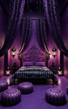 a bed with purple sheets and pillows in a room that has lights on the ceiling