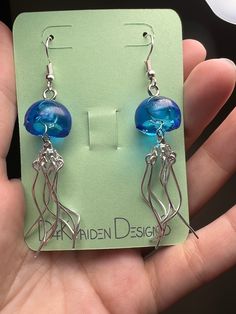 a pair of earrings with blue glass beads and silver wire are displayed in front of a card