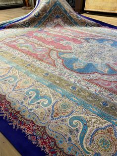 a large blue and red rug sitting on top of a wooden floor