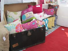 an assortment of colorful pillows on display in a room with red carpet and white walls