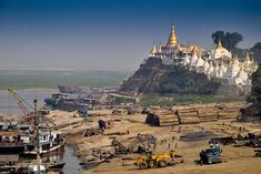 there are many boats and trucks on the beach near some buildings with gold spires in the background