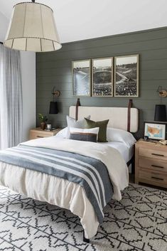 a bedroom with green walls, white bedding and two framed pictures on the wall