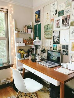 a laptop computer sitting on top of a wooden desk in front of a large window